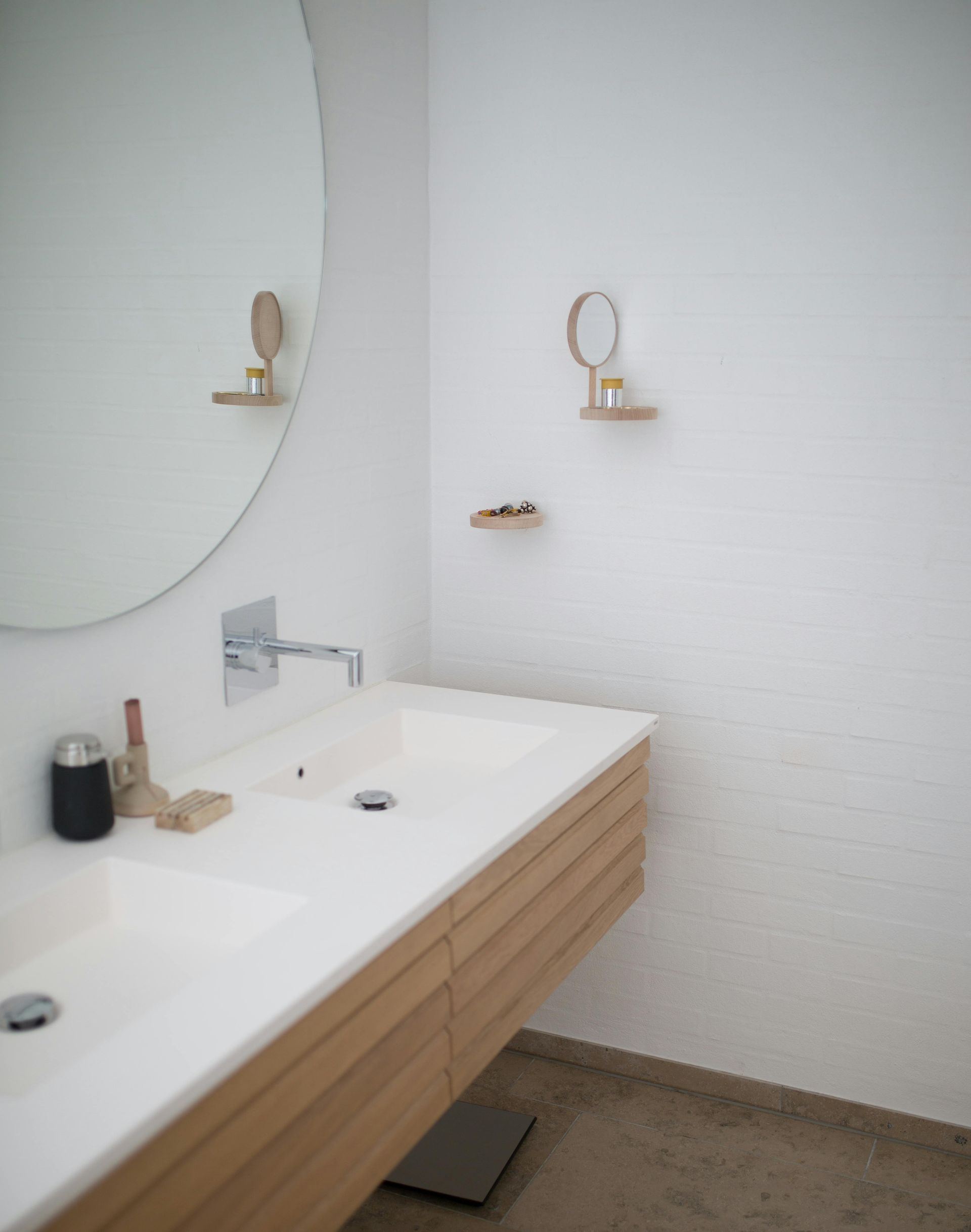 Floating wood vanity with an integrated white sink and round mirror
